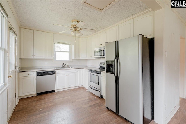 kitchen featuring appliances with stainless steel finishes, a textured ceiling, sink, and light hardwood / wood-style floors