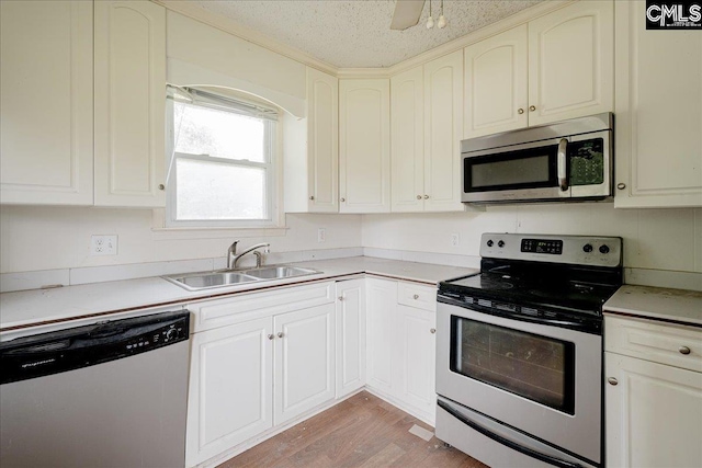 kitchen featuring sink, light hardwood / wood-style flooring, stainless steel appliances, and a textured ceiling