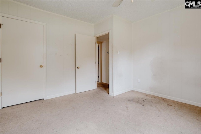 unfurnished bedroom with light carpet, a textured ceiling, and ceiling fan