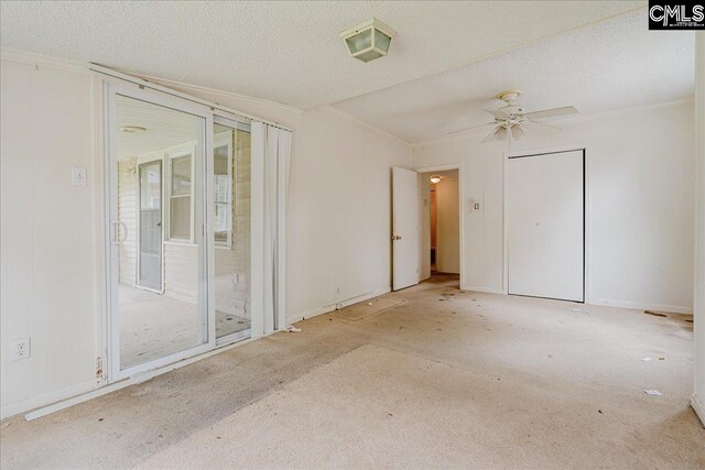 empty room with ceiling fan, a textured ceiling, ornamental molding, and light colored carpet