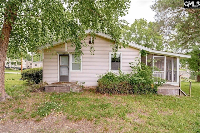 back of property with a yard and a sunroom