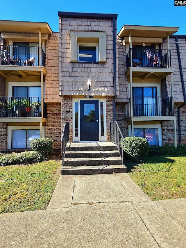 view of front facade featuring a balcony and a front lawn