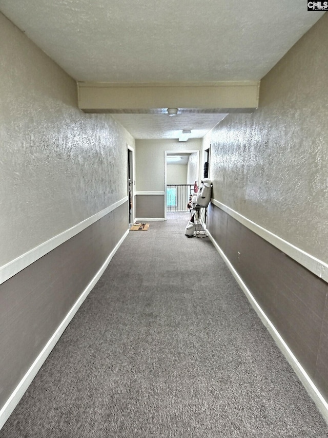 hall with a textured ceiling and carpet floors