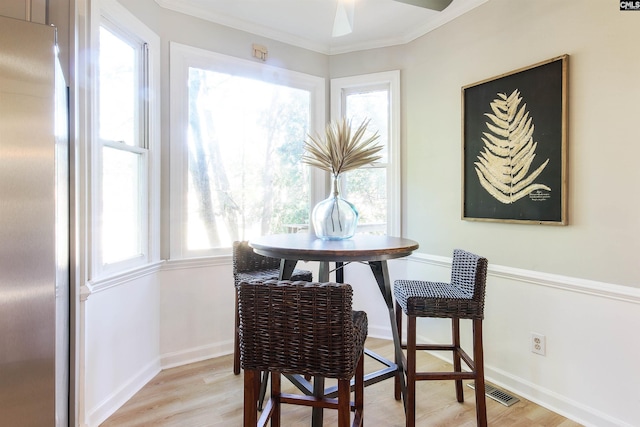 dining room with crown molding, a healthy amount of sunlight, and light wood-type flooring