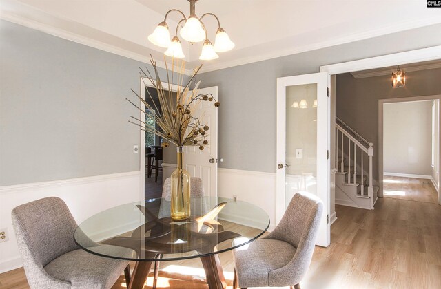 dining space with crown molding, a chandelier, and wood-type flooring