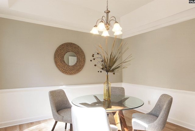 dining space with ornamental molding, hardwood / wood-style flooring, and a chandelier