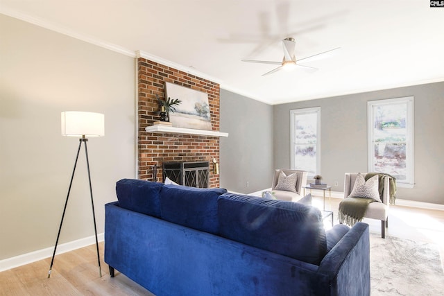 living room with a fireplace, ceiling fan, light wood-type flooring, and crown molding