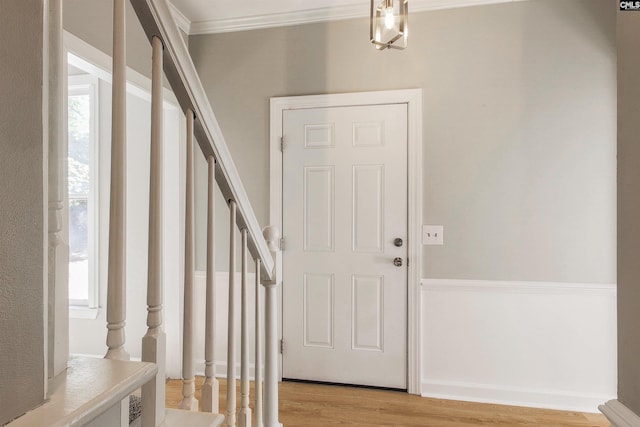 entrance foyer with light hardwood / wood-style floors, crown molding, and a healthy amount of sunlight