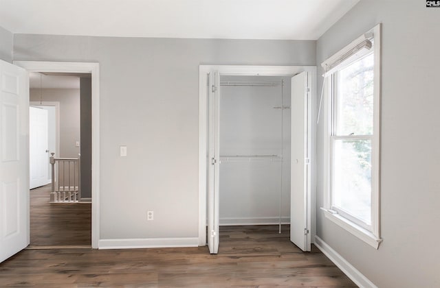 unfurnished bedroom with a closet and dark hardwood / wood-style floors