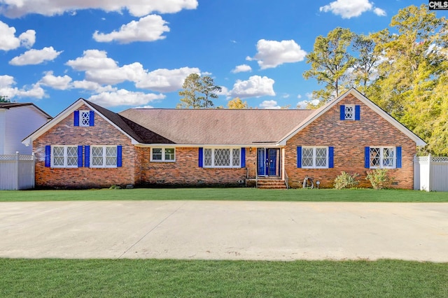 view of front of house featuring fence, roof with shingles, a front yard, and brick siding