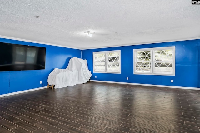 spare room featuring a textured ceiling, dark wood-type flooring, and plenty of natural light