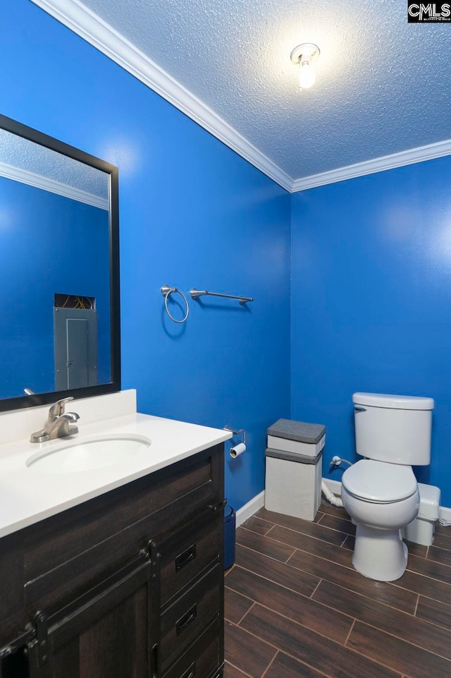 bathroom featuring toilet, hardwood / wood-style floors, crown molding, vanity, and a textured ceiling