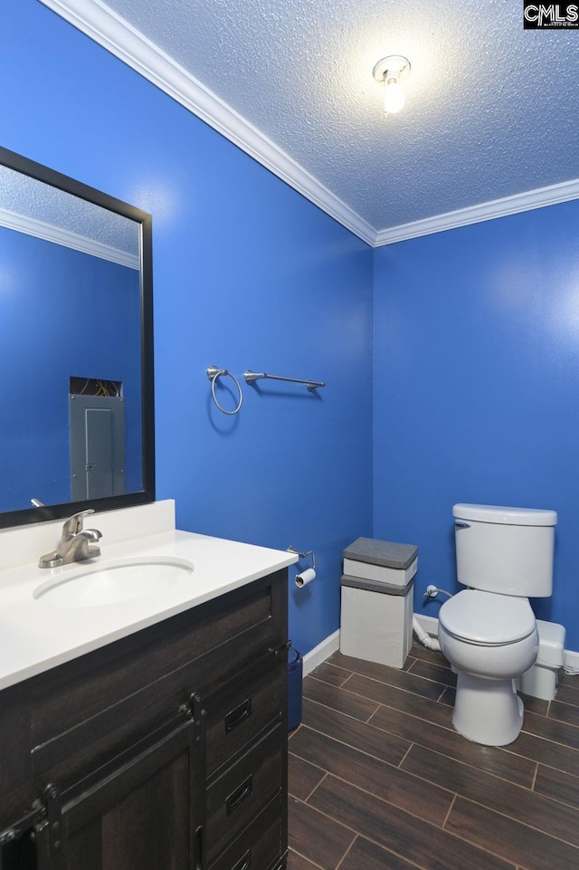 half bathroom with vanity, toilet, ornamental molding, wood finish floors, and a textured ceiling