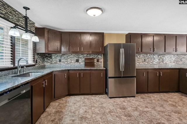 kitchen featuring hanging light fixtures, stainless steel appliances, dark stone counters, sink, and dark brown cabinetry