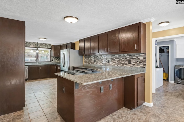 kitchen featuring kitchen peninsula, washer / clothes dryer, appliances with stainless steel finishes, light stone countertops, and ornamental molding