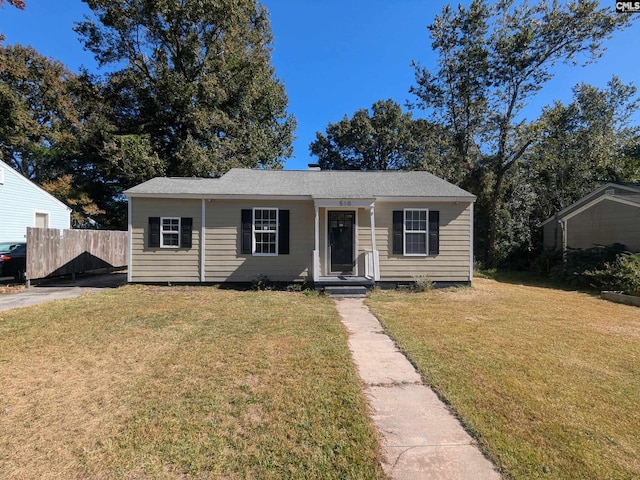 bungalow featuring fence and a front lawn