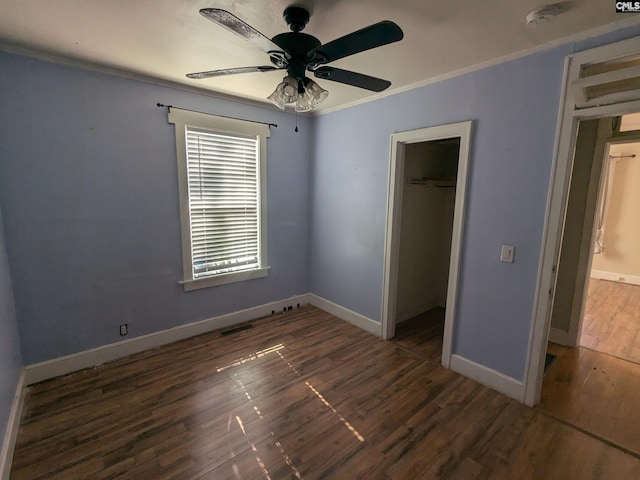 unfurnished bedroom with wood finished floors, a closet, ceiling fan, baseboards, and crown molding
