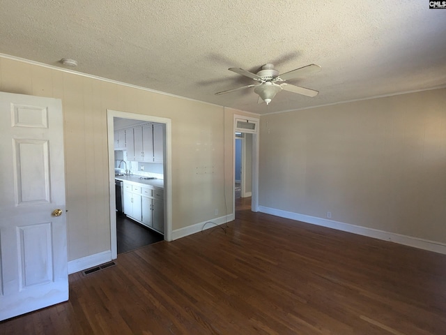 spare room featuring crown molding, a ceiling fan, visible vents, a textured ceiling, and dark wood finished floors