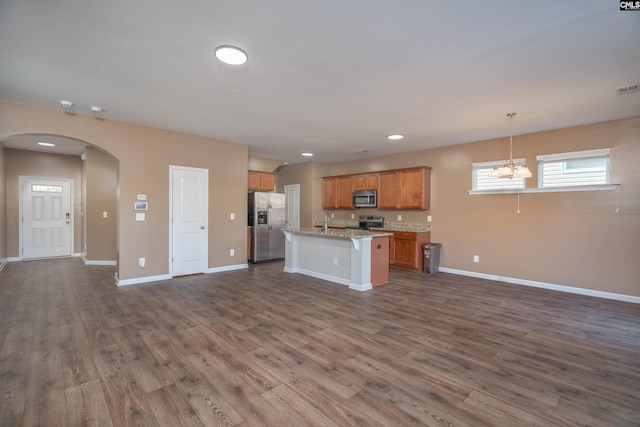 kitchen featuring open floor plan, hanging light fixtures, appliances with stainless steel finishes, and arched walkways