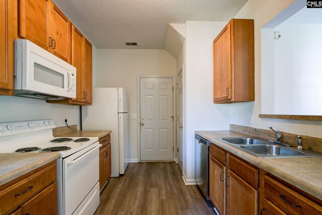 kitchen with sink, a textured ceiling, white appliances, and dark hardwood / wood-style flooring