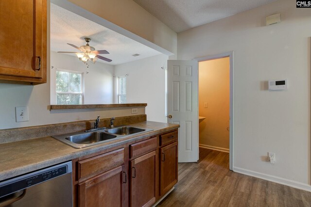 kitchen featuring hardwood / wood-style floors, ceiling fan, a textured ceiling, stainless steel dishwasher, and sink