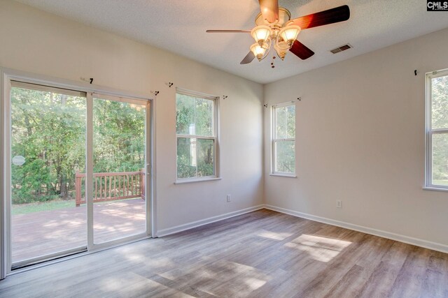 spare room with ceiling fan, plenty of natural light, and light wood-type flooring