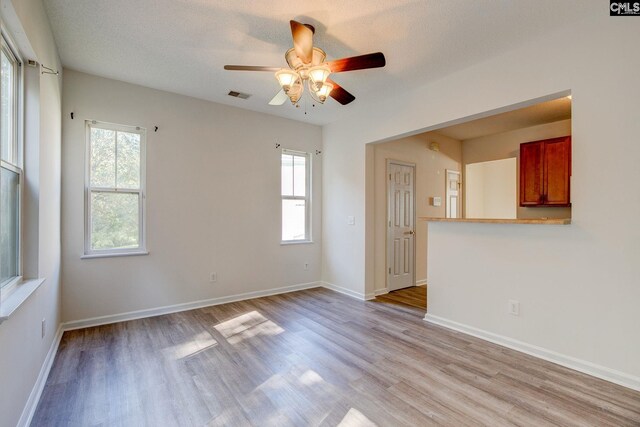 empty room with a healthy amount of sunlight, a textured ceiling, and light wood-type flooring