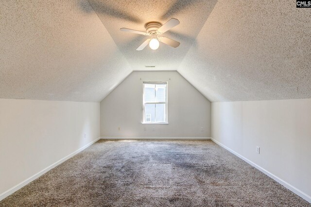 additional living space featuring vaulted ceiling, a textured ceiling, carpet floors, and ceiling fan