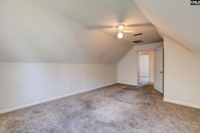 additional living space featuring ceiling fan, a textured ceiling, vaulted ceiling, and carpet floors