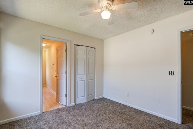 unfurnished bedroom featuring a closet, ceiling fan, light carpet, and a textured ceiling