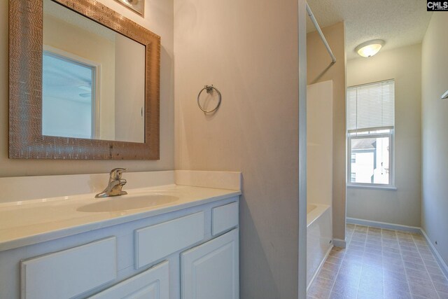 bathroom with vanity, a textured ceiling, and a tub