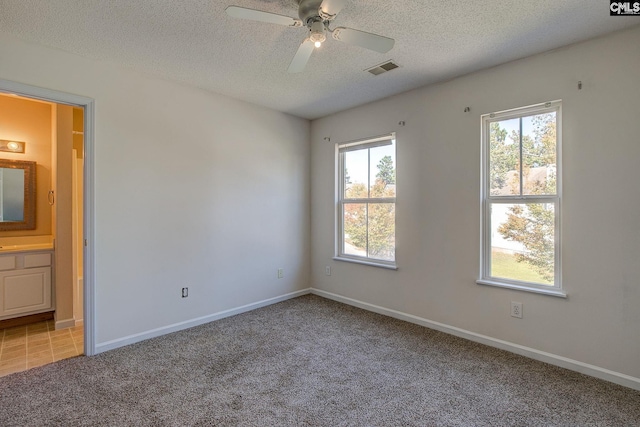 carpeted spare room with a textured ceiling and ceiling fan