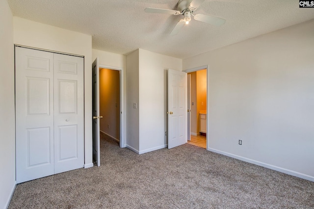 unfurnished bedroom with a textured ceiling, carpet flooring, a closet, and ceiling fan