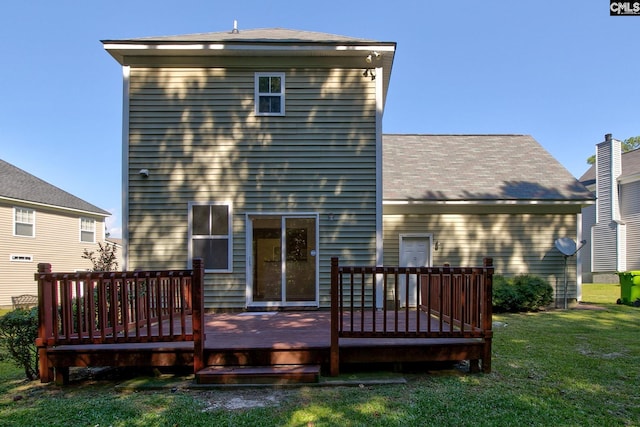 rear view of property featuring a wooden deck and a lawn