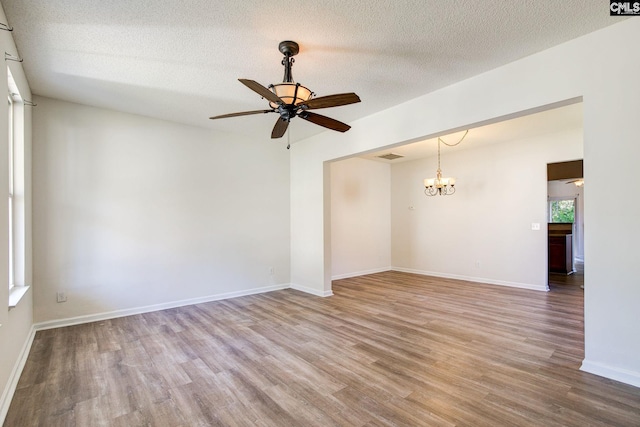 empty room with hardwood / wood-style floors, a textured ceiling, and ceiling fan with notable chandelier