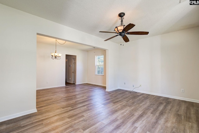 spare room with a textured ceiling, wood-type flooring, and ceiling fan with notable chandelier