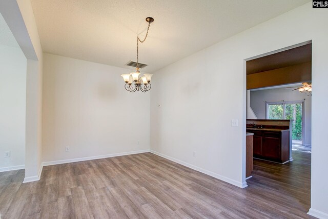 unfurnished room with sink, a textured ceiling, hardwood / wood-style flooring, and ceiling fan with notable chandelier