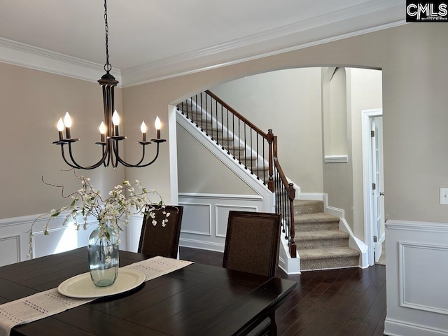 dining area featuring dark wood-type flooring, a notable chandelier, and crown molding