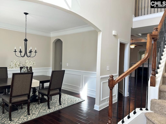 dining space with crown molding, dark wood-type flooring, and ceiling fan with notable chandelier