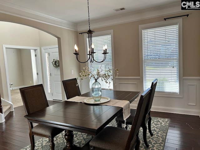 dining room with ornamental molding, dark hardwood / wood-style floors, and an inviting chandelier