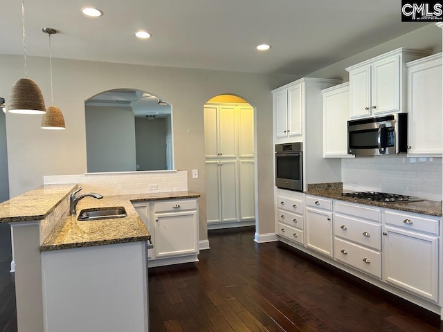 kitchen with hanging light fixtures, kitchen peninsula, sink, white cabinets, and appliances with stainless steel finishes