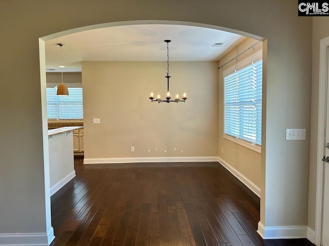 unfurnished dining area featuring a notable chandelier and dark hardwood / wood-style floors