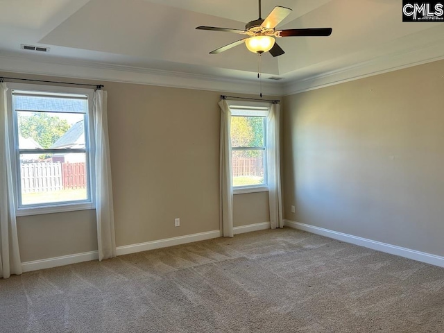 empty room with light carpet, crown molding, a tray ceiling, and ceiling fan