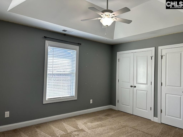 unfurnished bedroom with two closets, carpet, and ceiling fan