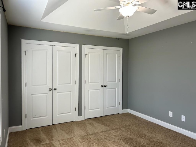 unfurnished bedroom with multiple closets, carpet, and ceiling fan