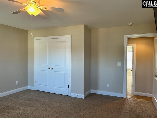 unfurnished bedroom with dark colored carpet, a closet, and ceiling fan