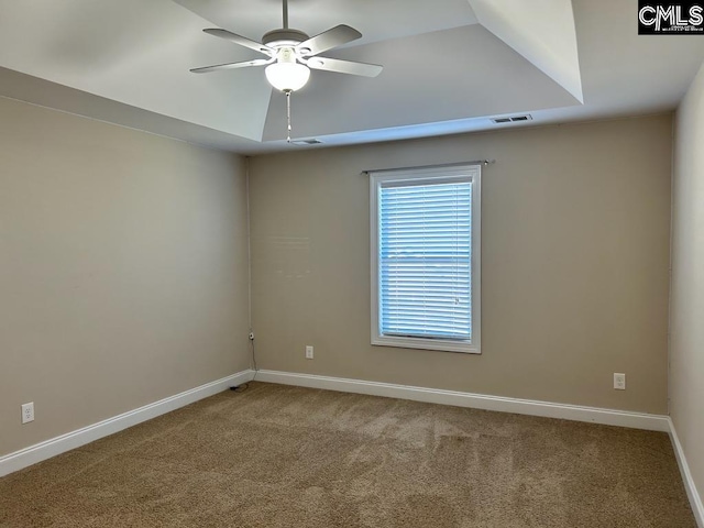 empty room with ceiling fan, a raised ceiling, and carpet