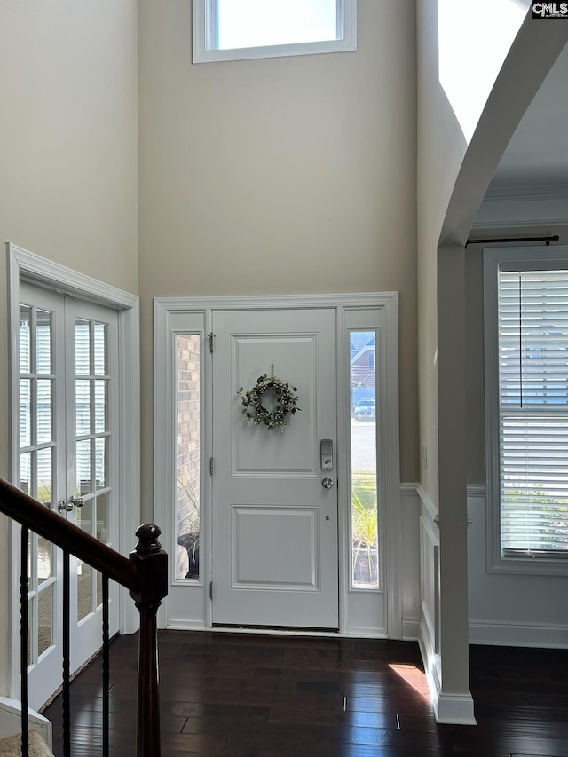 entryway with crown molding, a towering ceiling, dark hardwood / wood-style flooring, and plenty of natural light