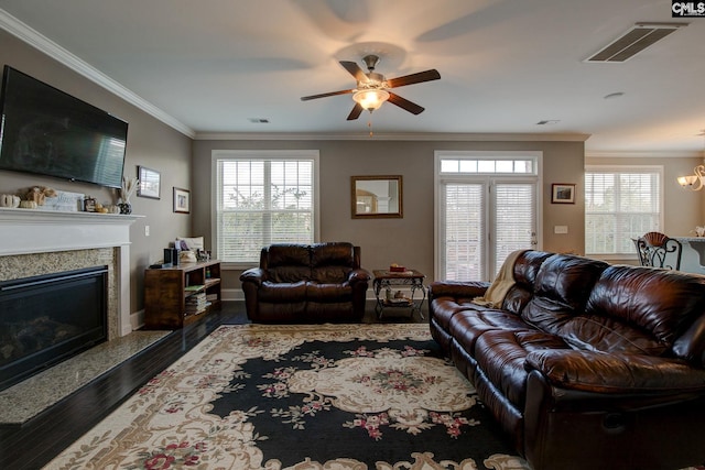 living room featuring dark wood-type flooring, a high end fireplace, a healthy amount of sunlight, and ornamental molding