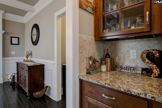 bar with dark wood-type flooring, light stone countertops, backsplash, and crown molding